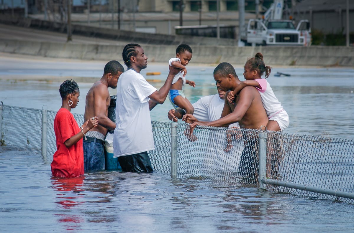 A family pass a toddler over a fence in New Orleans on August 30, 2005. (Kathy Anderson)